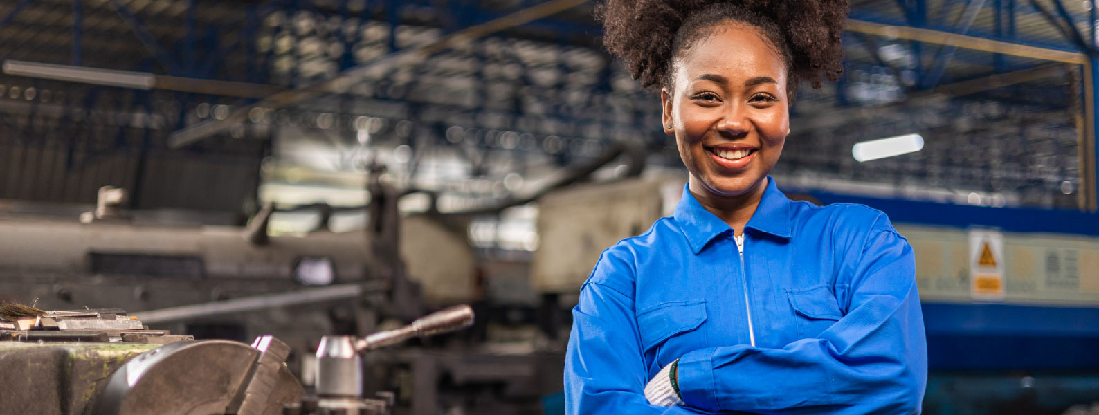 Woman in FR clothing smiling at camera in manufacturing facility
